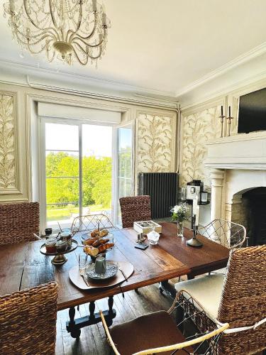 a dining room with a table and a fireplace at Demeure de la Garenne in Montmirail