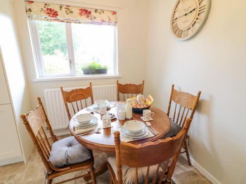 a dining room table with chairs and a clock on the wall at Glebe Farm Cottage in Newry