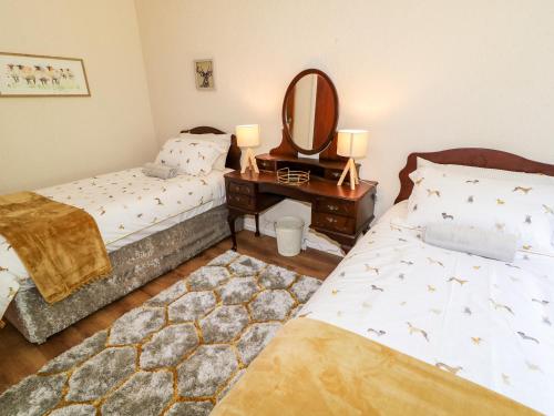 a bedroom with two beds and a mirror and a table at Glebe Farm Cottage in Newry