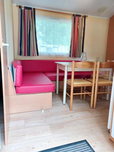 un salon avec un canapé rouge et une table dans l'établissement Charmant Bungalow à Saint-Pierre-d'Oléron avec Jardin, à Saint-Pierre-dʼOléron