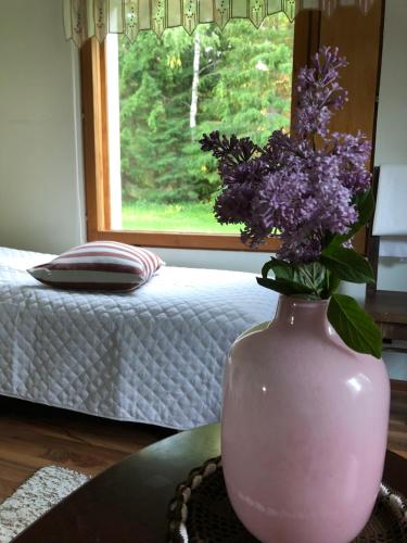 a pink vase with purple flowers on a table at Pakola in Viitasaari