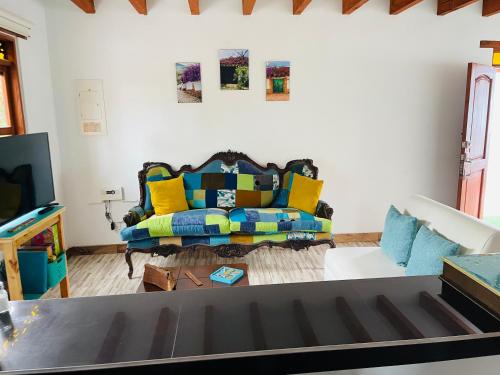 a living room with a couch with yellow and blue pillows at Casa turquesa in Villa de Leyva