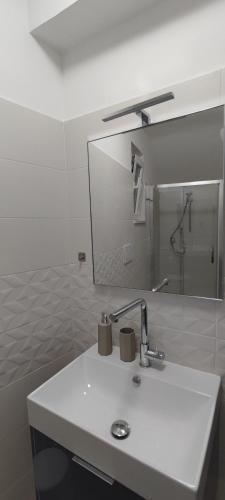 a white bathroom with a sink and a mirror at Giù da Nonna in Gaeta