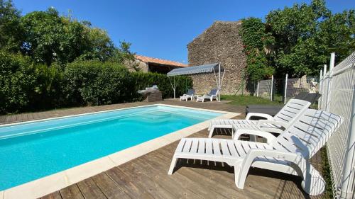 a swimming pool with lounge chairs next to a swimming pool at Gîte La Maison de Bosc in Coutens