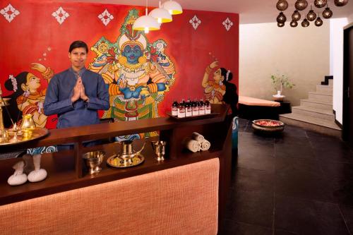 a man standing at a bar in a room with a painting at Sterling Munnar in Munnar