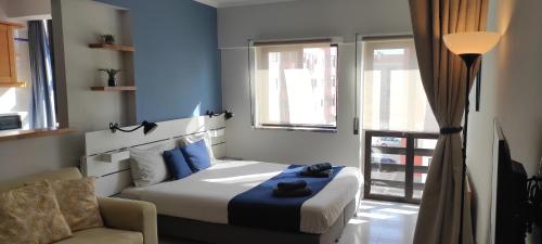 ペニシェにあるBaleal Holidays - Peniche Sunny Apartmentのベッドルーム1室(ベッド1台、ソファ、窓付)