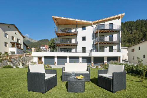 a group of chairs sitting in the grass in front of a building at ROTUND-Nature_Mountain_Living in Tubre