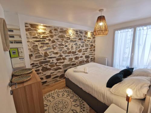 1 dormitorio con 1 cama grande y pared de piedra en L'Escale - Les Maisons de Madeleine, en Bouguenais