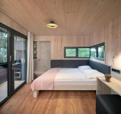 a bedroom with a large bed and some windows at Baumhaus im Vogelgesang in Heuchelheim-Klingen
