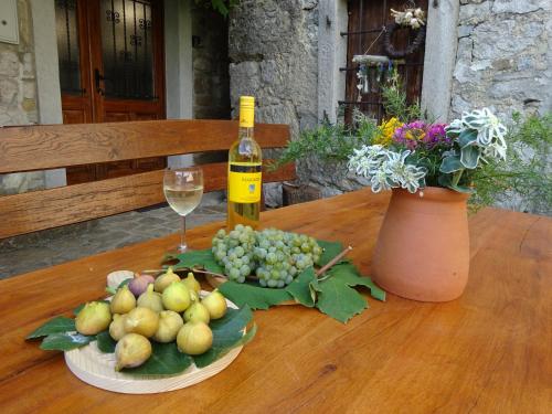 een fles wijn en een fruitschaal op een houten tafel bij Pri kovačih, Istra autentica 