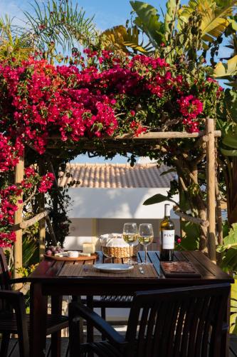 a table with glasses of wine and pink flowers at Vila Luz in Luz