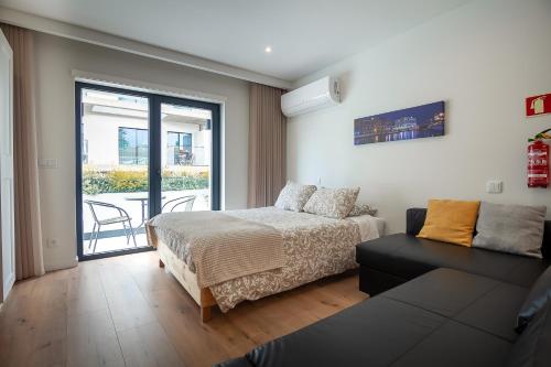 - une chambre avec un lit, un canapé et un balcon dans l'établissement Gravito 53 Apartments by Home Sweet Home Aveiro, à Aveiro