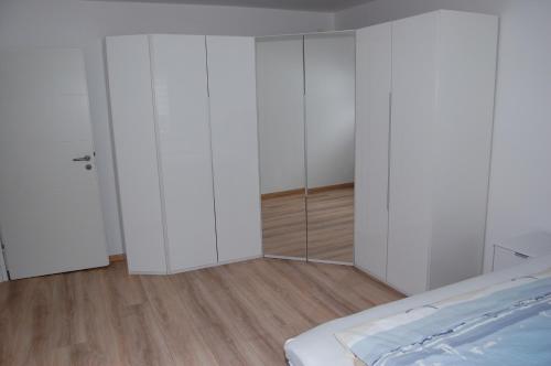 a bedroom with white cabinets and a bed and wooden floors at Ferienwohnung Stollenwerk am Steinhuder Meer An der Schanze 13 in Steinhude