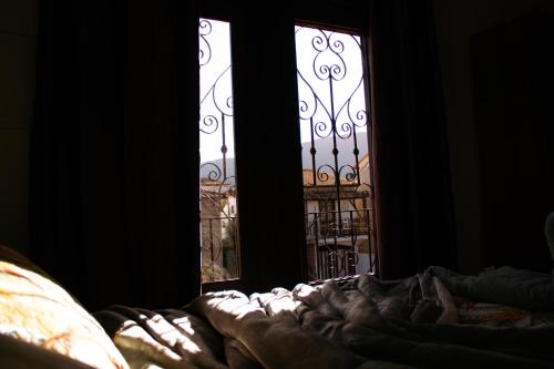 a bed in a dark room with two windows at Pouso Primavera in Tiradentes