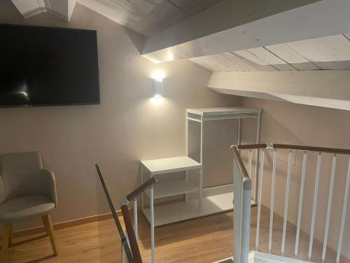 a room with a staircase with a tv and a chair at Palazzo Sarti Suites in Rodi Garganico