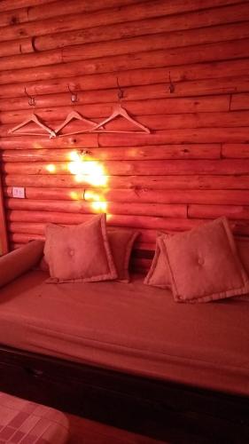 a bed in a room with a wooden wall at cabaña la casa del arbol in Tandil