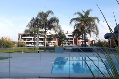 a building with palm trees and a swimming pool at Fabuloso departamento en complejo residencial in Yerba Buena