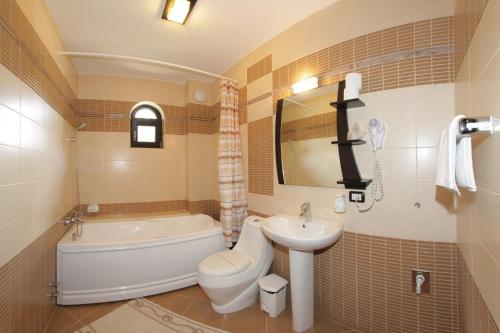 a bathroom with a sink and a toilet and a bath tub at Hotel Victoria in Borşa