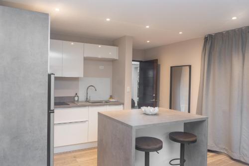 a kitchen with a island with two stools and a counter at Tradewinds Apartments Simpson Bay in Simpson Bay