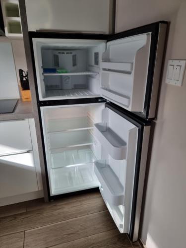 an empty refrigerator with its door open in a kitchen at Tradewinds Apartments Simpson Bay in Simpson Bay