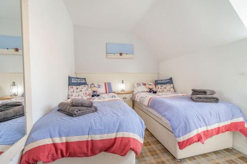 a bedroom with two beds and a mirror at Lilipad Cottage in Reighton