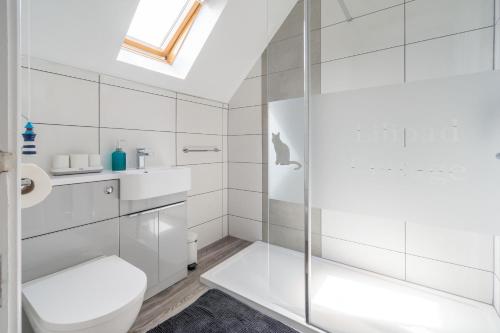 a white bathroom with a shower and a toilet at Lilipad Cottage in Reighton