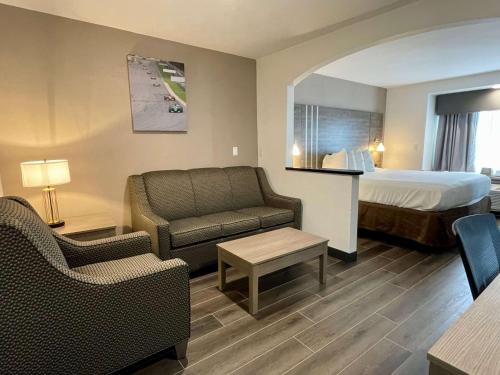 a hotel room with a bed and a couch and chair at Best Western Roanoke Inn & Suites in Roanoke