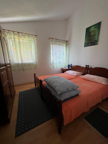 a bedroom with two beds and two windows at Apartments Akiki in Karlobag