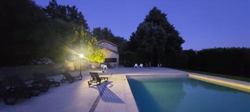 a swimming pool with chairs next to a house at Quinta do Carvalho - Nature Guest Houses in Guimarães