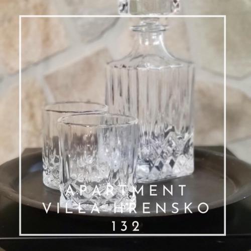a glass bottle and two glasses sitting on a table at Apartment Villa Hřensko 132 in Hřensko