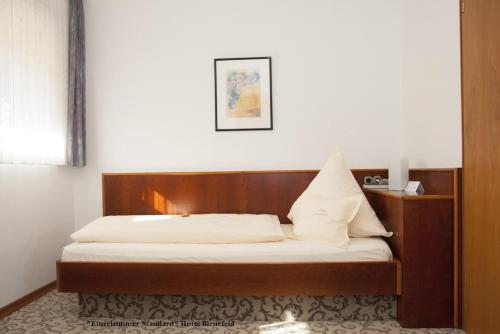 a bed with a wooden headboard in a room at Hotel Bienefeld in Korschenbroich