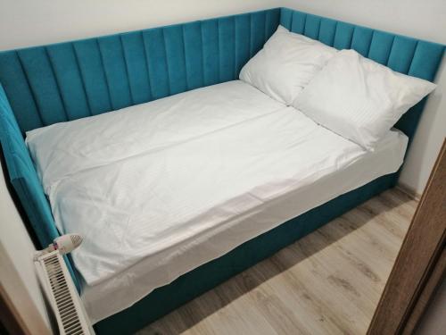 1 cama con cabecero azul y sábanas y almohadas blancas en Apartament Przy Parku en Malbork