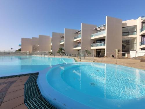 a large swimming pool in front of a building at Cozy 1 Bedroom Apartment with Sea View in Cotillo