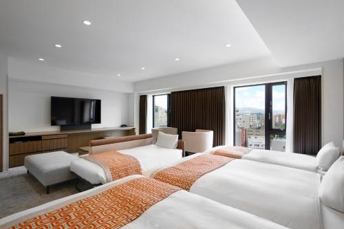 a hotel room with three beds and a flat screen tv at Daiwa Roynet Hotel Morioka Ekimae in Morioka