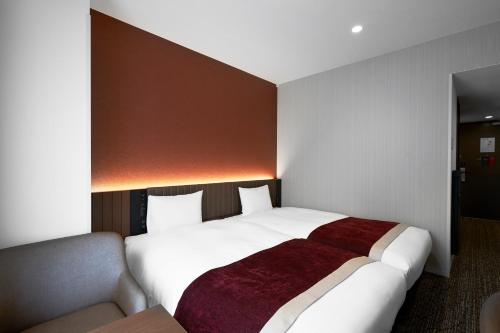 a hotel room with a large bed and a couch at Daiwa Roynet Hotel Morioka Ekimae in Morioka