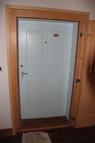 a white door in a room with a wooden wall at Dolomites Holidays in Selva di Cadore