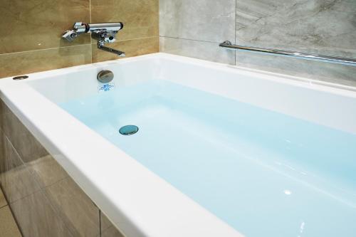 uma banheira branca com uma torneira na casa de banho em Daiwa Roynet Hotel Morioka Ekimae em Morioka
