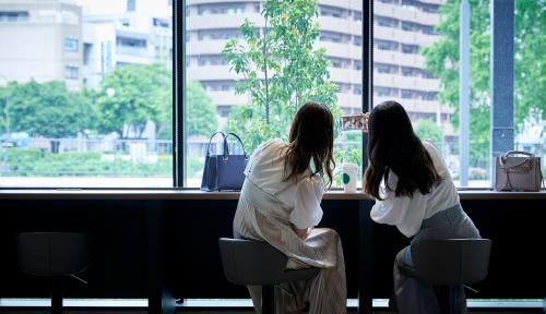zwei Frauen, die am Tresen sitzen und aus dem Fenster schauen in der Unterkunft Daiwa Roynet Hotel Morioka Ekimae in Morioka