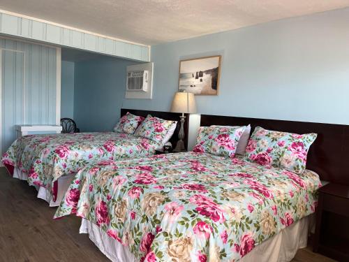 1 dormitorio con 2 camas con ropa de cama con motivos florales en Pete's Lakefront Motel, LLC en Geneva