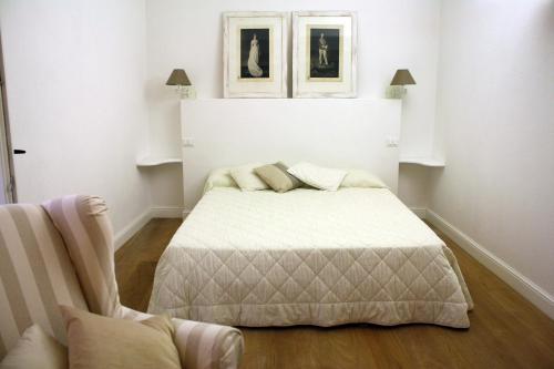 um quarto branco com uma cama e uma cadeira em La dimora del Conte Bracco B. em Albenga