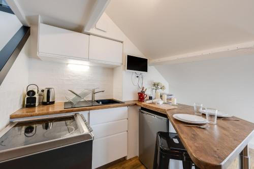 une cuisine avec des armoires blanches et un comptoir en bois dans l'établissement Le Saphir - Joli Studio en plein centre ville avec Climatisation, à Annecy