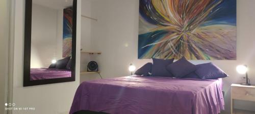 a bedroom with a purple bed with a painting on the wall at Parrot House San Antonio in Cali