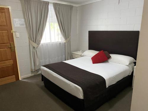 a bedroom with a bed with a red pillow on it at Puffers Inn in Loganholme