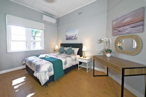 a bedroom with a bed and a desk and a mirror at Cozy 3BRM Holiday Staycation Bendigo Lakeside Pet Friendly Free Wifi in Bendigo