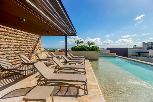 a group of lounge chairs next to a swimming pool at Sea Breezes Studio at Syrena 409 in Playa del Carmen