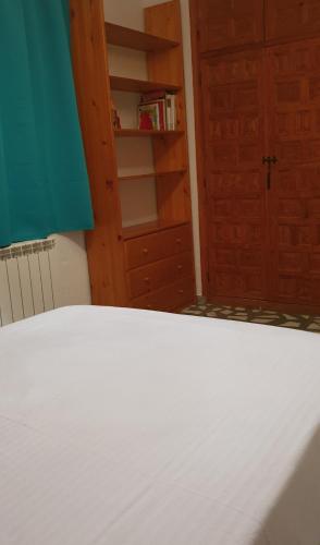 a bedroom with a white bed and a book shelf at Casa con Encanto Mitos in Pelayos del Arroyo