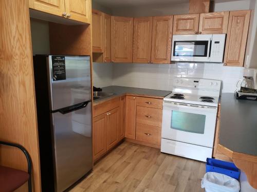 a kitchen with wooden cabinets and a stainless steel refrigerator at Lamplighter Inn in Three Hills