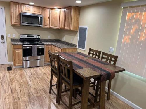 uma cozinha com uma mesa de madeira com cadeiras e um fogão em Nunaka Valley Cottage em Anchorage