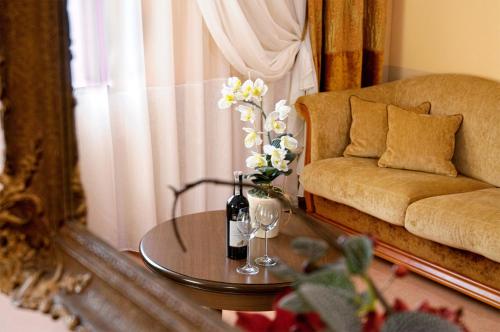 a living room with a table with a bottle of wine and flowers at Hotel Aleksander in Włocławek
