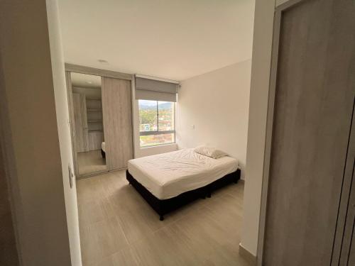 a small bedroom with a bed and a window at Apartamento con piscina y parqueadero a 7 min del centro in Villeta